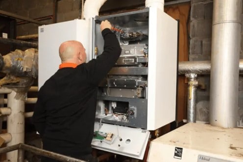 Heating engineer carrying out a boiler repair for a commercial heating system